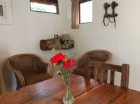 Cottage 4 Kitchenette, flowers on a table with two chairs. Wall decorations in the background.